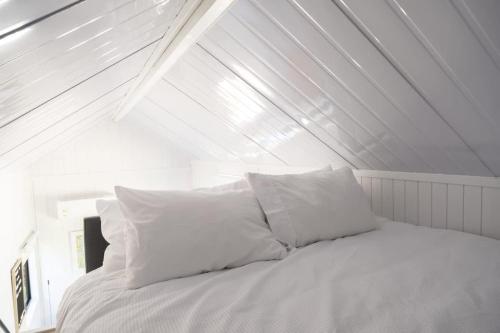 un letto con lenzuola e cuscini bianchi in una stanza di Tiny Away Benger Garden 1 a Millers Flat