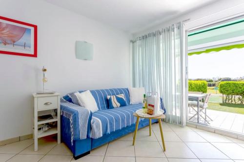 uma sala de estar com um sofá azul e uma porta de vidro deslizante em Chez Catherine - Superbe T3 idéalement placé en bord de plage em La Grande-Motte