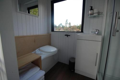 een kleine badkamer met een toilet en een raam bij Breathe Inn in Kaitaia