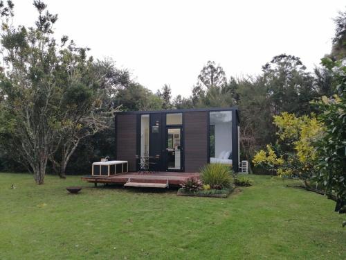 a tiny house in a garden with a deck at Creekside at Kuaotunu in Matarangi