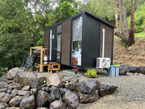 a black tiny house sitting on top of a pile of rocks at Cosy Dell in Herbert