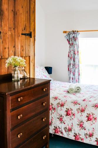 a bedroom with a bed and a dresser with flowers on it at Boss’s farmhouse in Valentia Island