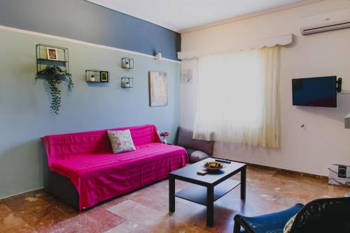 a living room with a pink couch and a table at Relaxation apartment in Messini