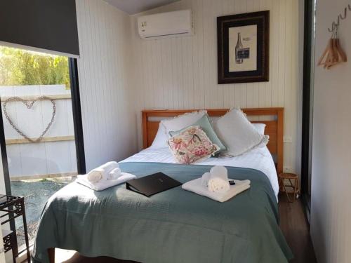 a bed with two towels and a book on it at The Hide Away Cabin in Redwoods Valley