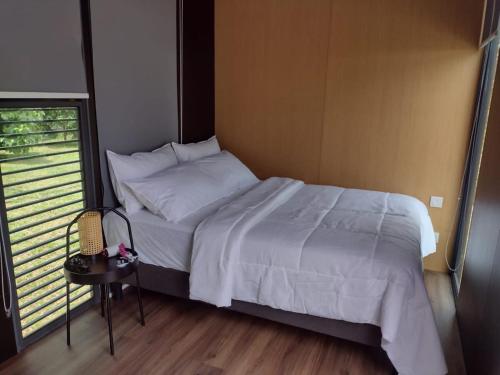 a bedroom with a bed and a table and a window at Sungai Tiny House 2 in Raub