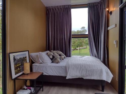 a bedroom with a bed and a large window at Sungai Tiny House in Raub