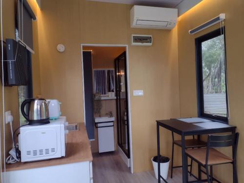 a kitchen with a microwave and a table in a room at Sungai Tiny House in Raub