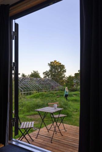 a table and chairs on a deck with a view of a field at Ammebergs Blommor by Tiny Away in Åmmeberg