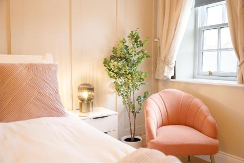 a bedroom with a bed and a chair and a plant at Northern Hideaways, Eider Cottage, Seahouses in Seahouses