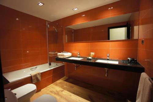 Buil & Gine Wine Hotel في غراتالوبس: حمام به مغسلتين وحوض استحمام ومرآة