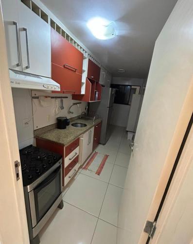 uma pequena cozinha com armários vermelhos e um fogão em Apartamento próximo a praia em Maceió