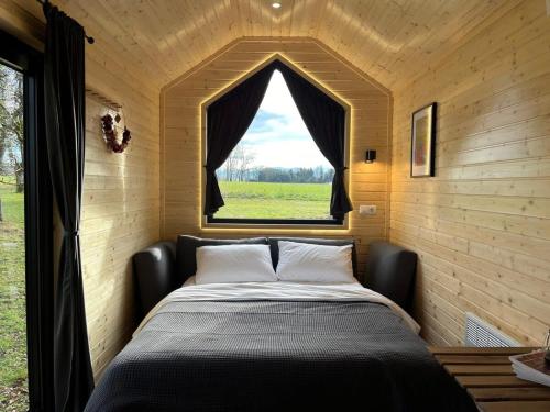 Bett in einem kleinen Zimmer mit Fenster in der Unterkunft Lisi Grun Tiny House in Sattledt
