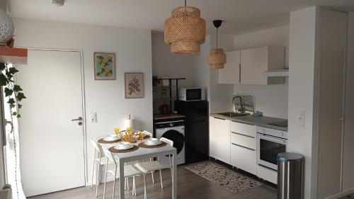 une cuisine avec une petite table et des placards blancs dans l'établissement Charmant appartement cosy et paisible proche Paris - métro à 2min, à Romainville
