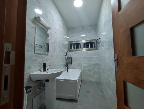 biała łazienka z umywalką i toaletą w obiekcie La résidence le Mirifique w mieście Kribi