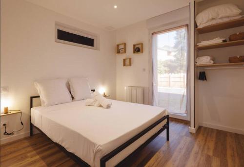 ein Schlafzimmer mit einem großen weißen Bett und einem Fenster in der Unterkunft L'Aindus de Brou- parking privé- RDC in Bourg-en-Bresse