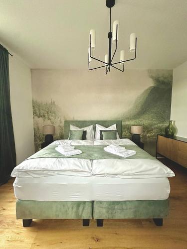 a bedroom with a large bed with a chandelier at betterplaces: Boutique Apartments - Frontenhausen in Dingolfing