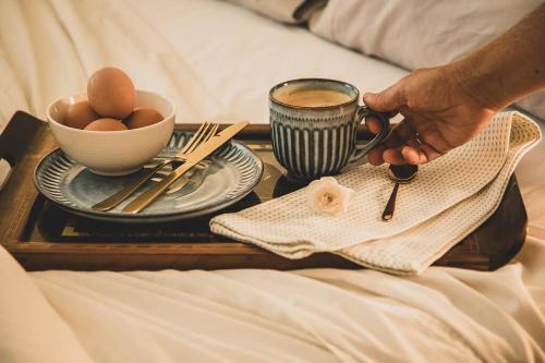 a tray with a cup of coffee and eggs on a bed at Snowy Valleys iconic stay - Moonshiner Cottage @ Distillery in Tumbarumba