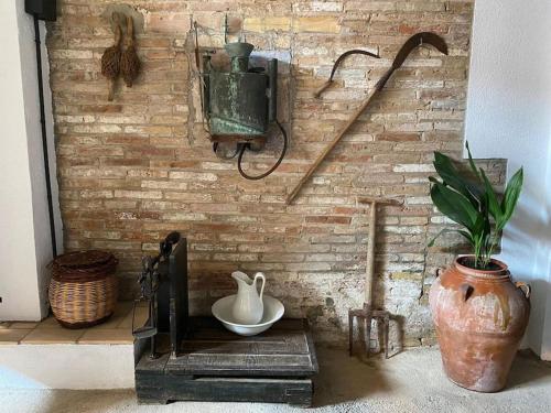 a brick wall with a vase and a pot on a shelf at Ca la Trini - turisme rural in Torrellas de Foix
