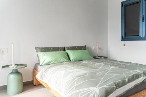 een witte slaapkamer met een bed met groene kussens bij SOL in Tijarafe