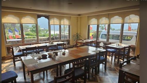 a dining room with tables and chairs and windows at Divine heritage house in Punākha