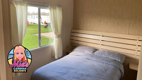 a small bedroom with a bed and a window at The Cosalt Torbay Caravan in Ingoldmells