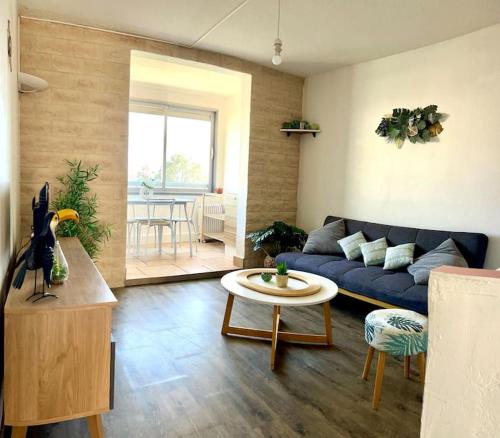 un salon avec un canapé bleu et une table dans l'établissement Miroir de la mer, appartement vue mer pied dans l eau, à Fréjus