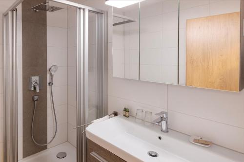 een badkamer met een wastafel en een douche met een spiegel bij Hotel Seestern in Wasserburg