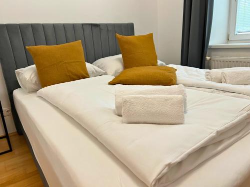 three white beds with yellow pillows on top of them at Leoben City Apartments - Premium Apartments 24 7 in Leoben