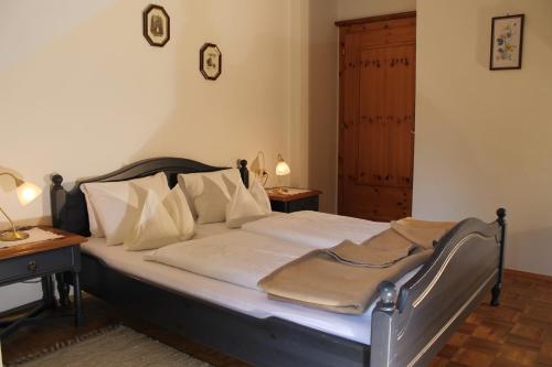 ein Bett mit weißer Bettwäsche und Kissen in einem Schlafzimmer in der Unterkunft Haralds Ferienwohnungen in Bad Kleinkirchheim