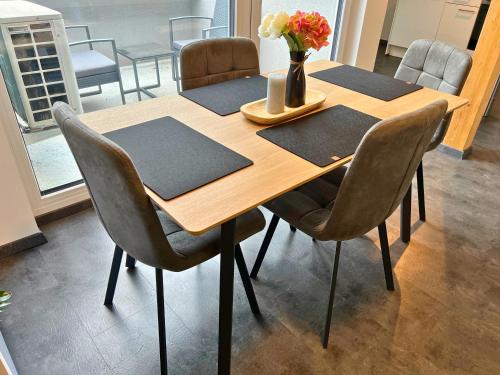 a wooden table with chairs and a vase of flowers on it at Leoben City Apartments - Premium Apartments 24 7 in Leoben