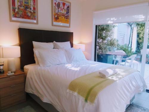 1 dormitorio con 1 cama blanca grande y ventana en Dressage B&B, en Ciudad del Cabo