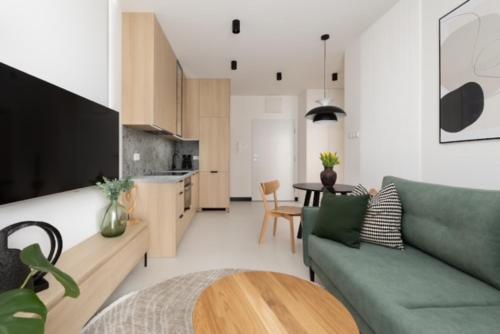 JTB Apartamenty Centrum في شتتين: غرفة معيشة مع أريكة خضراء وطاولة
