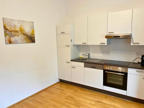a kitchen with white cabinets and a sink and a refrigerator at Leoben City Apartments - Premium Apartments 24 7 in Leoben