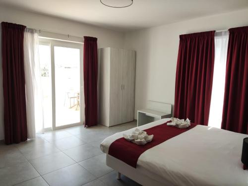 a bedroom with a large bed with red curtains at Fisherman's Cove Guesthouse in Marsaxlokk