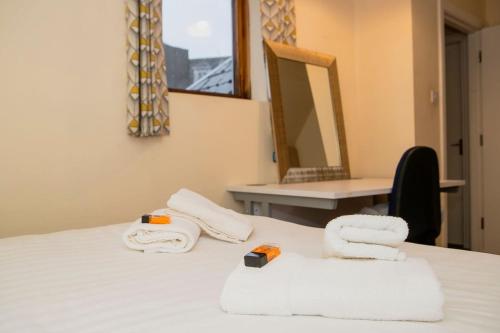 a room with a bed with towels and a mirror at City Centre Gem in Galway
