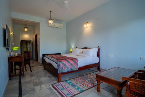 a bedroom with a bed and a chair and a table at Koolwal Kothi Zinc Journey by The Fern, Nawalgarh, Rajasthan in Nawalgarh