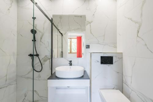 a white bathroom with a sink and a shower at Apartamenty AdMar in Krynica Morska
