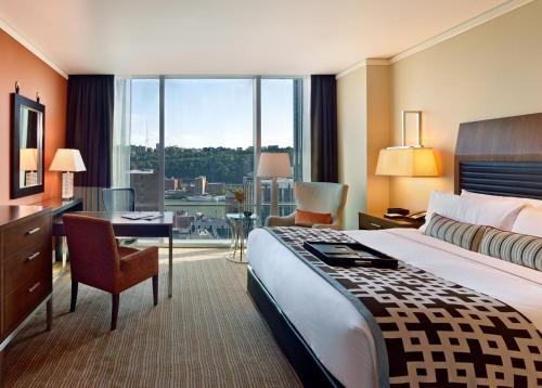 a hotel room with a bed and a desk and a large window at Fairmont Pittsburgh in Pittsburgh