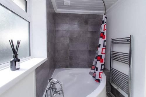 ein Bad mit einer Badewanne und einem Duschvorhang in der Unterkunft K Suites - Rowley Road in Dudley