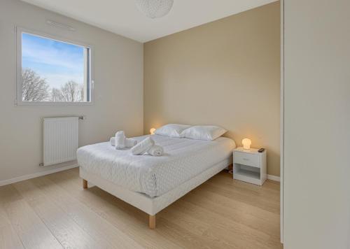 a white bedroom with a bed and a window at Le Ruffa in Bohars