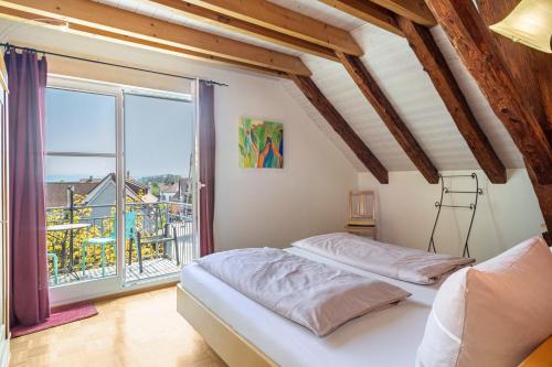 2 Betten in einem Zimmer mit einem großen Fenster in der Unterkunft Obst- Ferienhof Ragg in Immenstaad am Bodensee