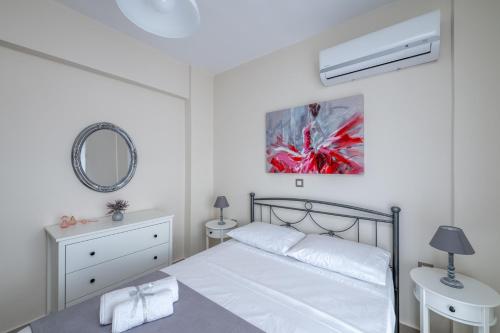a white bedroom with a bed and a mirror at Nimarevi Apartment in Soroni