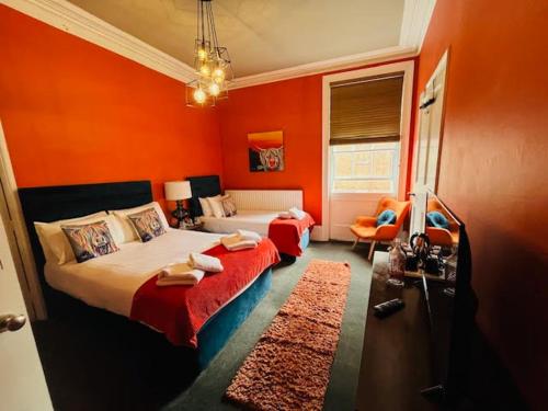 a bedroom with two beds and an orange wall at horn and trumpet in Bewdley