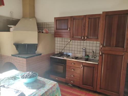 uma cozinha com armários de madeira e um forno com placa de fogão em Oasi ristoro dell' Etna em Piedimonte Etneo