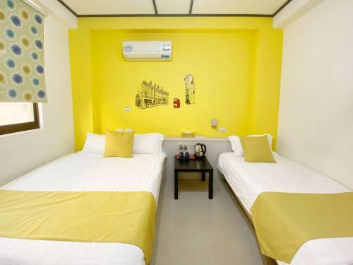 2 camas en una habitación con paredes amarillas en 小蘋果民宿, en Jinning