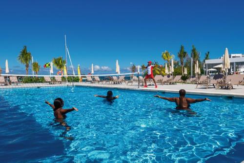 three children are swimming in a swimming pool at Riu Montego Bay - Adults Only - All Inclusive in Montego Bay