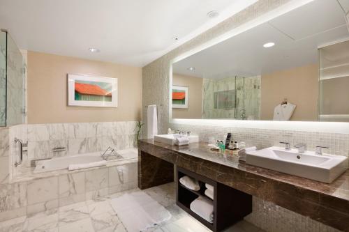 a bathroom with two sinks and a tub and a large mirror at Fairmont Pittsburgh in Pittsburgh