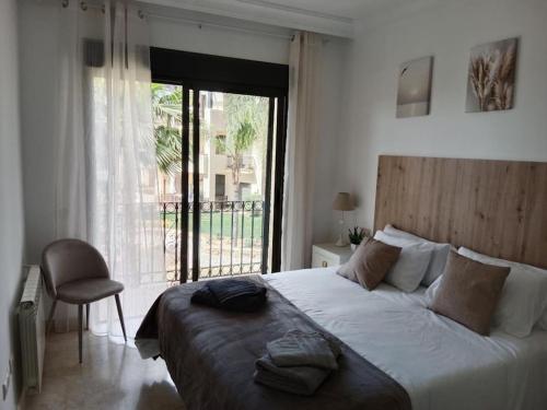 a bedroom with a large bed and a large window at El Oasis de Roda Golf Apartment in San Javier