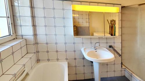 ein Badezimmer mit einem Waschbecken, einer Badewanne und einem Spiegel in der Unterkunft Ferienwohnung Stelzl in Sankt Johann im Saggautal