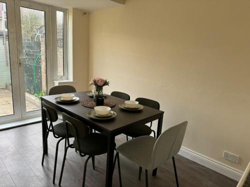 a dining room table with chairs and a vase of flowers at Entire three bedrooms house in London